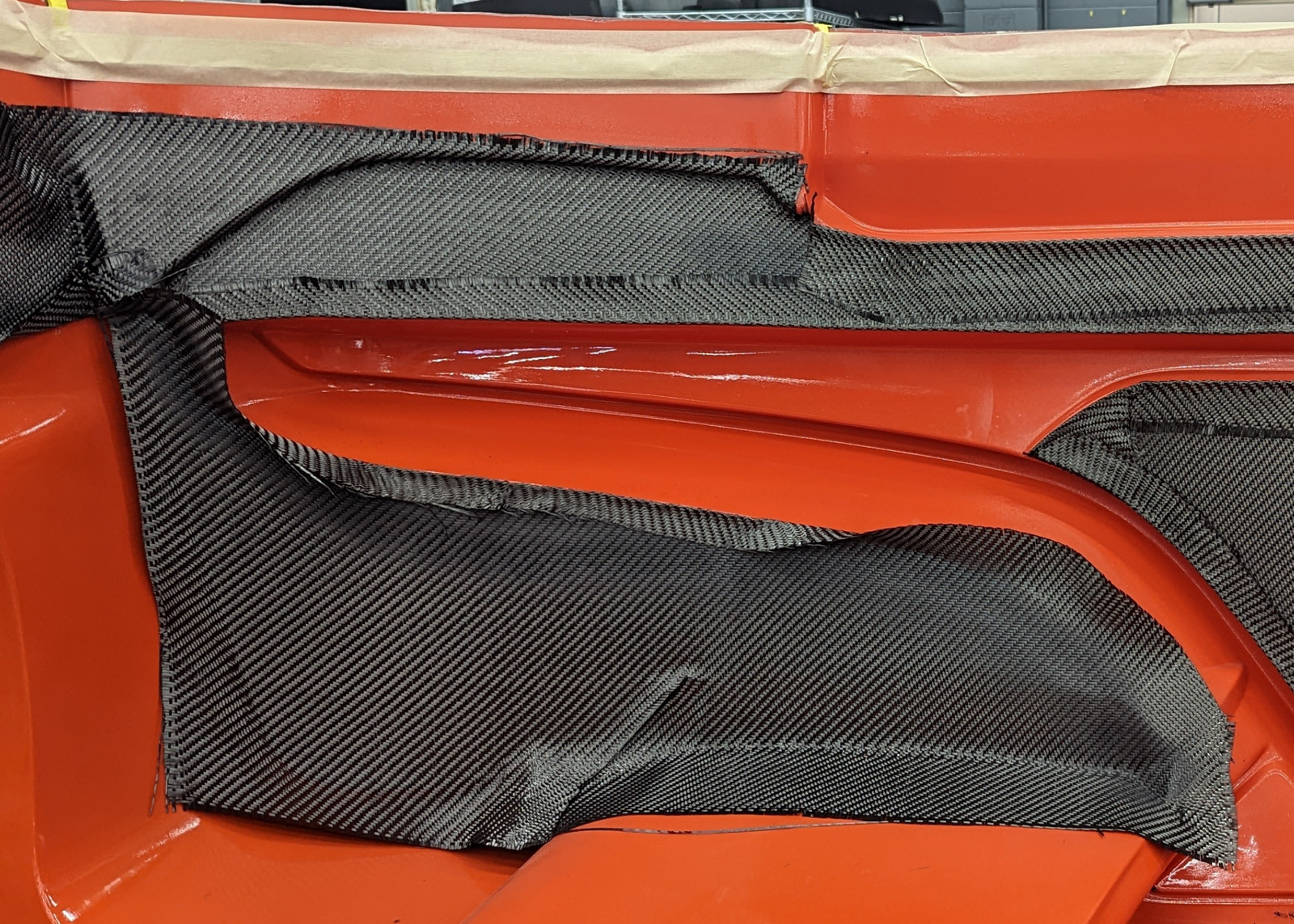 an orange fiberglass mold with a carbon fiber layup halfway started.