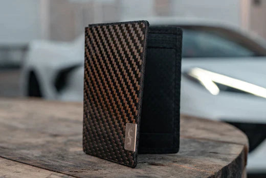 Common Fibers carbon fiber minimalist wallet on table with car behind